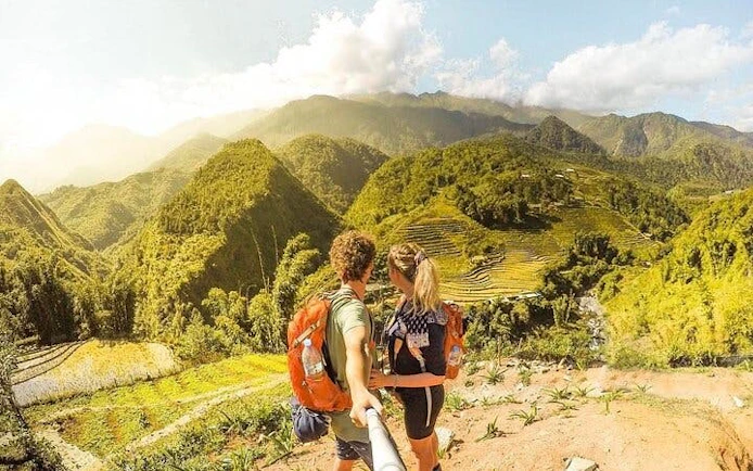 Couple trekking with backpacks overlooking rice terraces in Sapa, Vietnam.