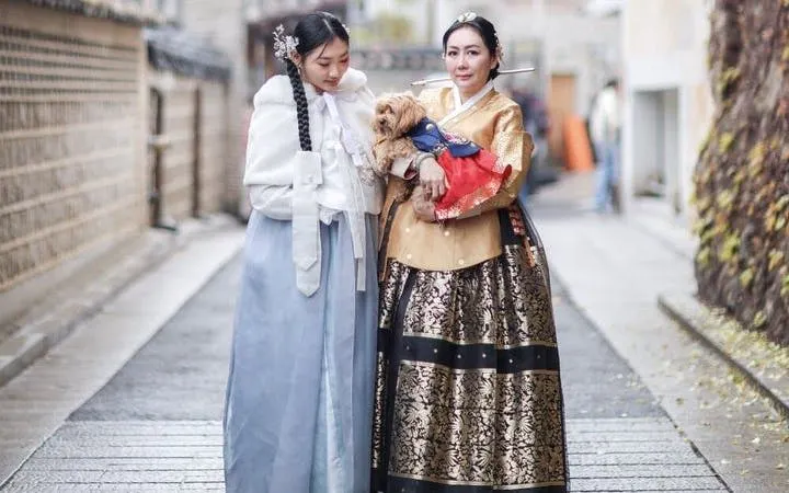 Women in traditional hanbok holding a dog at Gyeongbokgung Palace, Seoul.