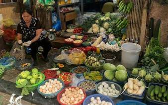 Hanoi street market vendor with fresh produce and eggs, part of Hanoi Highlights Vespa Tour.