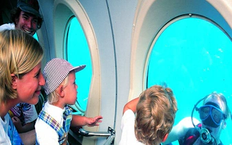 Family observing diver through submarine window on Tenerife tour.
