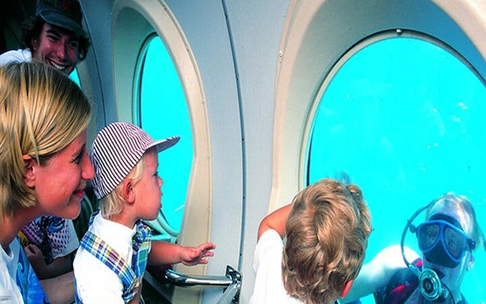 Family observing diver through submarine window on Tenerife tour.