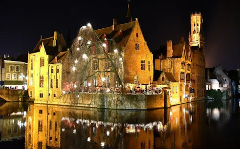Bruges canal-side buildings illuminated at night, part of self-guided walking tour via mobile app.