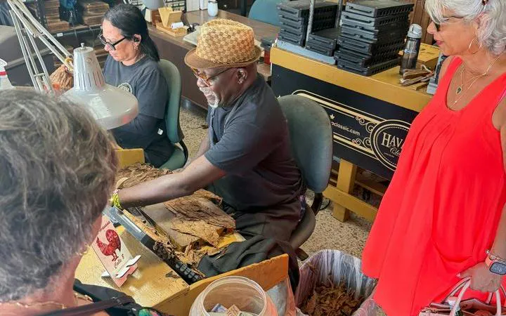 Cigar maker demonstrating rolling techniques to tourists in Little Havana, Miami.