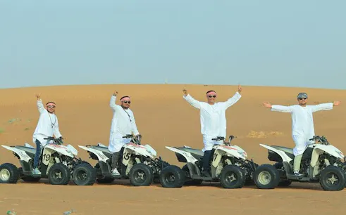 Quad biking in the desert during a morning safari with dune bashing and camel ride.