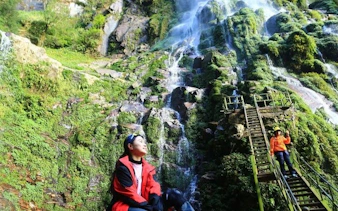 Sapa jungle trek to Queen Bee Waterfall with tourists on stairs and lush greenery.