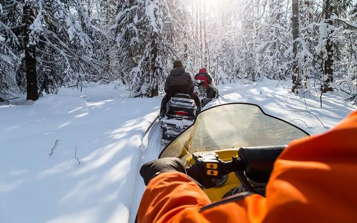 Snowmobiles driving through snowy forest in Zakopane during guided adventure tour.