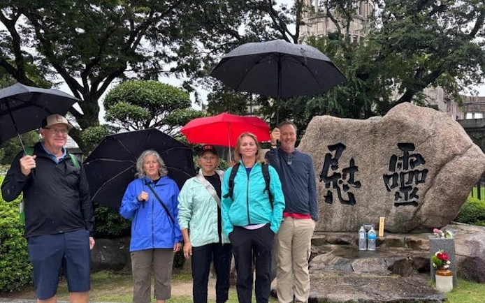 Visitors with umbrellas at Hiroshima Peace Memorial Park near Atomic Bomb Dome.