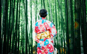 Person in kimono walking through Arashiyama Bamboo Forest in Kyoto.
