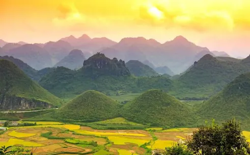 Ha Giang Loop mountains at sunset with lush green valleys and terraced fields.