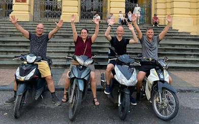 Group on motorbikes in front of Hanoi building, part of Hanoi City Motorbike Tour.