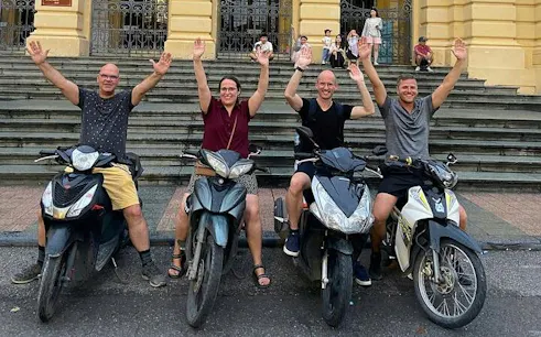 Group on motorbikes in front of Hanoi building, part of Hanoi City Motorbike Tour.