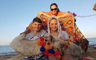 Camel ride with tourists on a beach in Sharm El Sheikh, colorful decorations on camel.