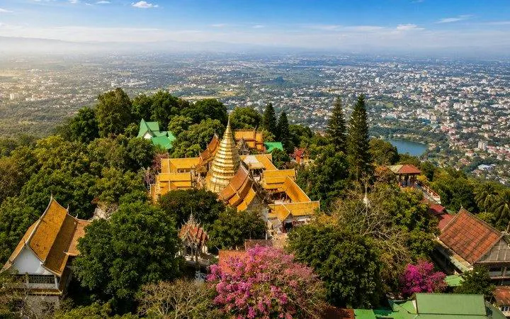 Aerial view of Wat Doi Suthep temple complex surrounded by lush greenery in Chiang Mai.