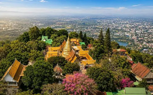 Aerial view of Wat Doi Suthep temple complex surrounded by lush greenery in Chiang Mai.