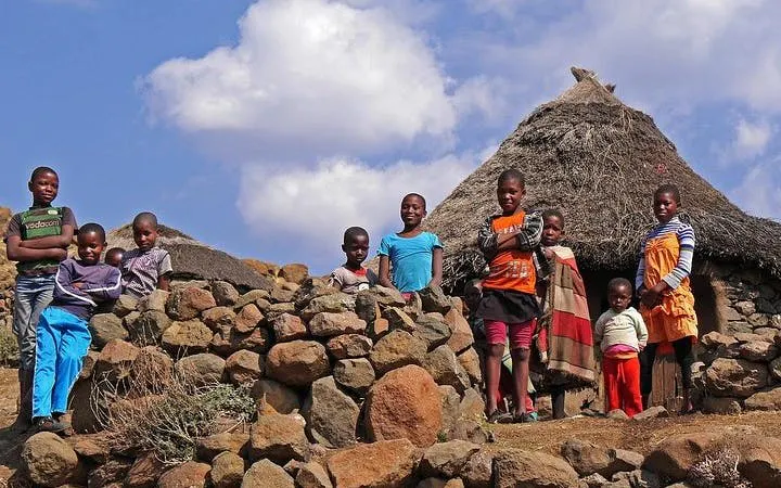 Children standing by traditional stone huts in Lesotho during Sani Pass tour from Durban.