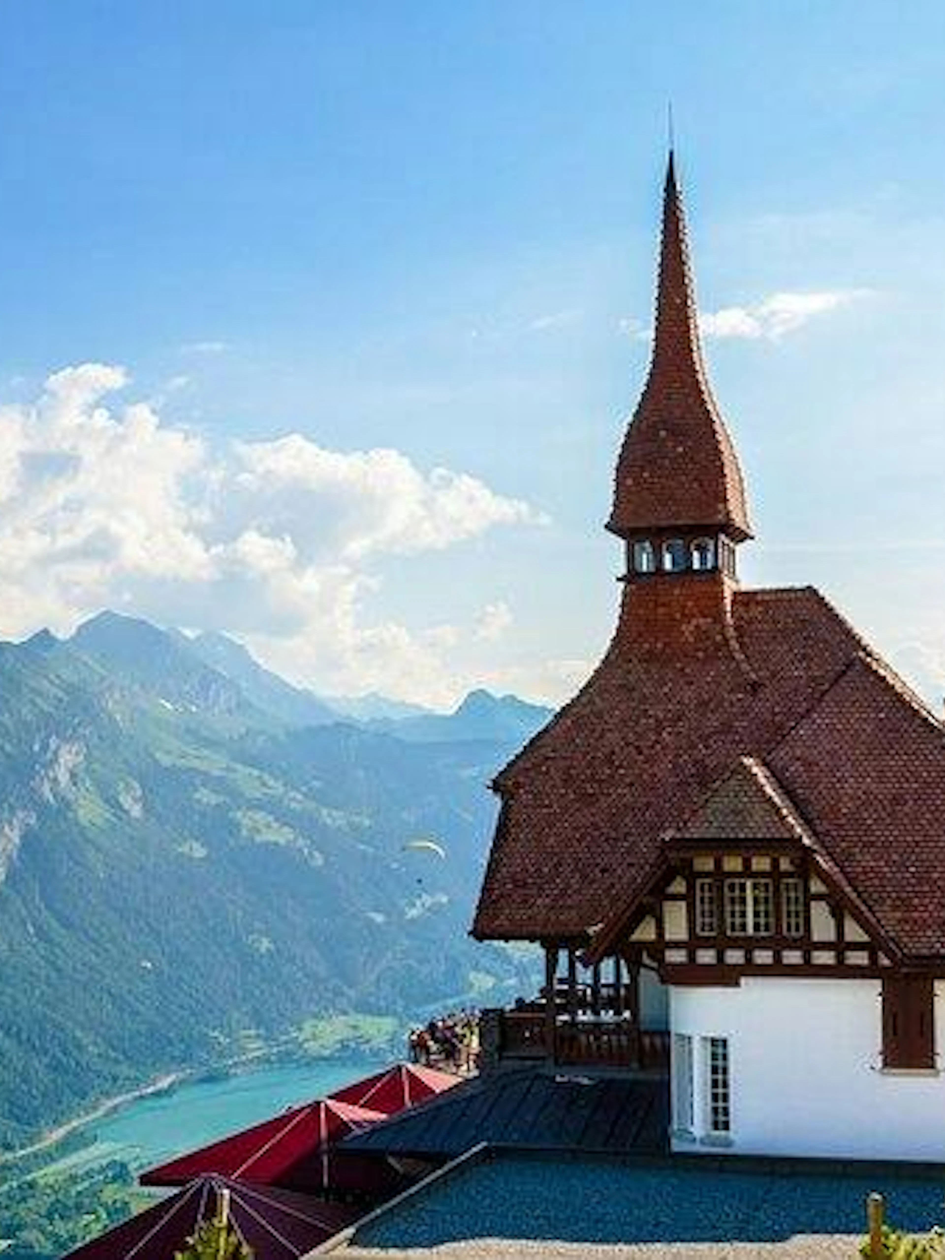 Paraglider over Lake Brienz with Swiss chalet and Bernese Alps in background, Lucerne tour.