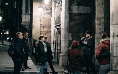 Group listening to a guide during York haunted history walking tour at night.