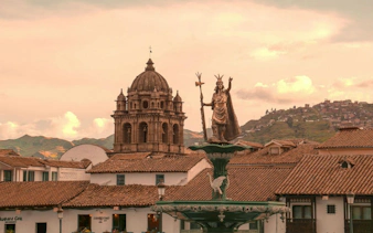 Cusco Cathedral dome and Inca statue in Plaza de Armas, Cusco, Peru.