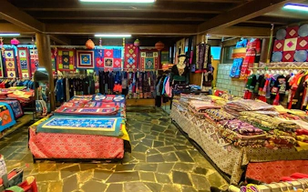 Traditional textiles and garments displayed in a Sapa market shop during a cultural tour.