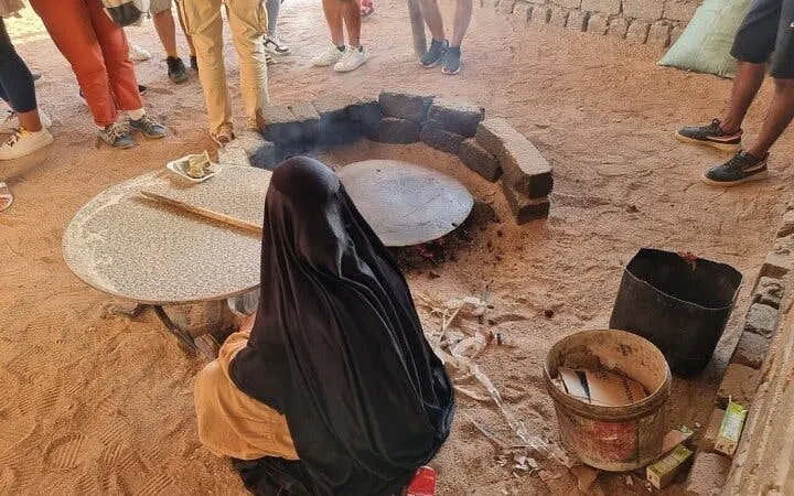 Woman preparing traditional bread on sand during ATV safari in Sharm El Sheikh.