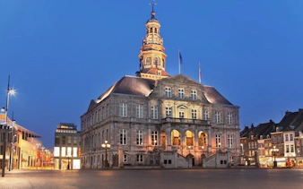 Maastricht Town Hall illuminated at dusk during self-guided walking tour.
