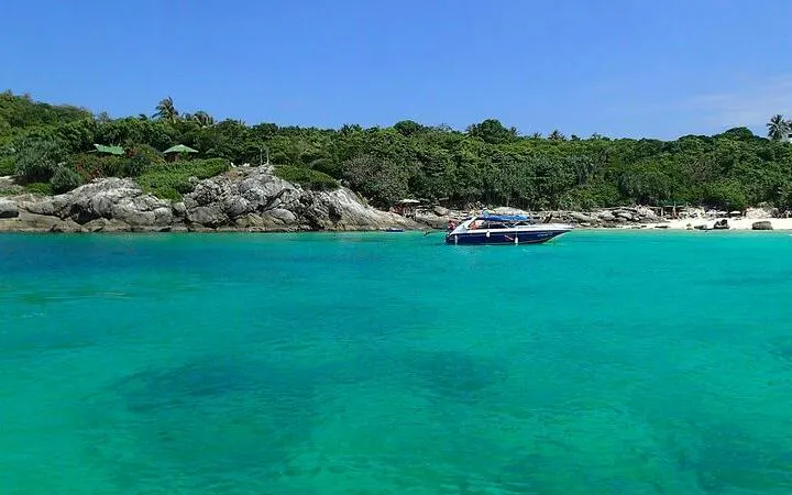 Speedboat anchored near Banana Beach, Koh Hey, with clear turquoise water and lush greenery, Phuket.