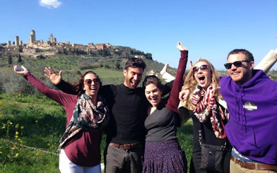 Group enjoying Chianti wineries tour with San Gimignano in the background.