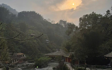 Sapa landscape with traditional buildings and misty hills at sunset.