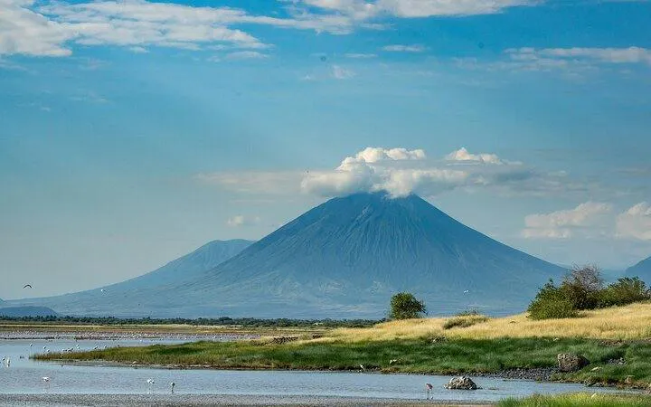 Volcano near Lake Natron with grassy shoreline, part of 3-day safari from Arusha to Tarangire National Park.