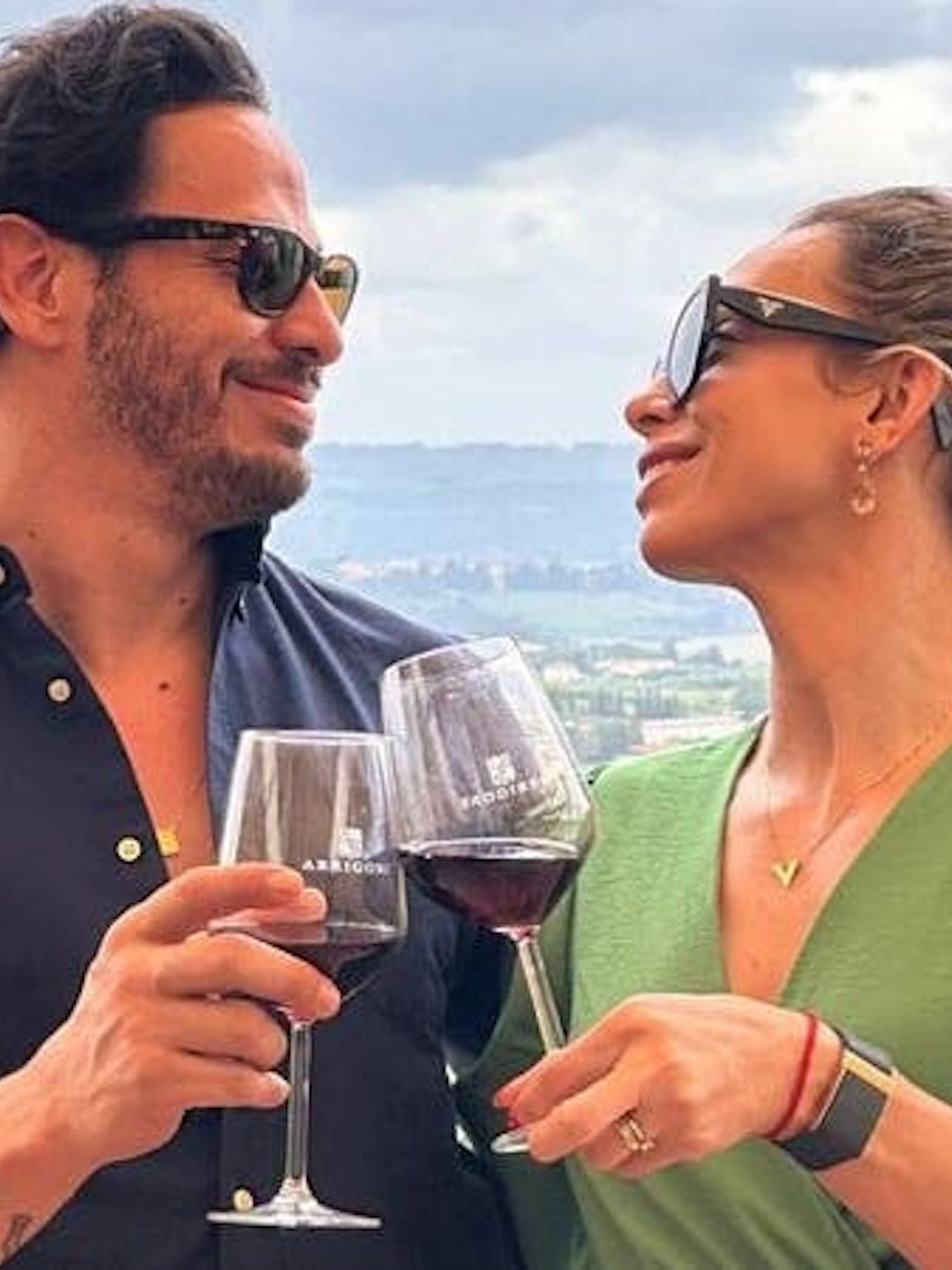 Couple toasting with wine overlooking Chianti vineyards during a vintage Fiat 500 tour.