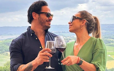 Couple toasting with wine overlooking Chianti vineyards during a vintage Fiat 500 tour.