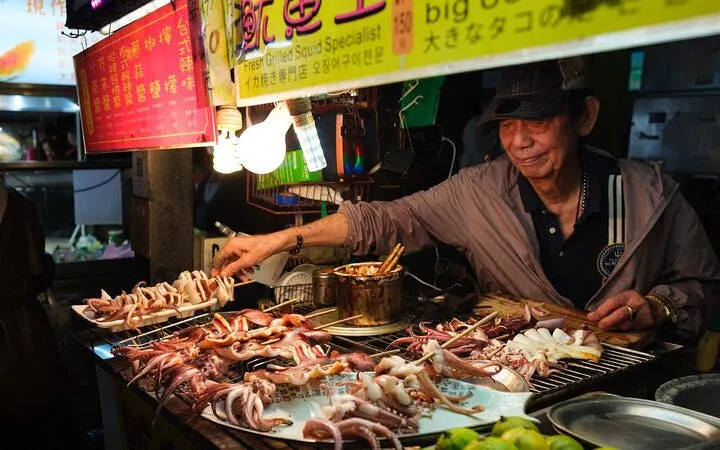 Vendor grilling squid at a Taipei night market food tour.