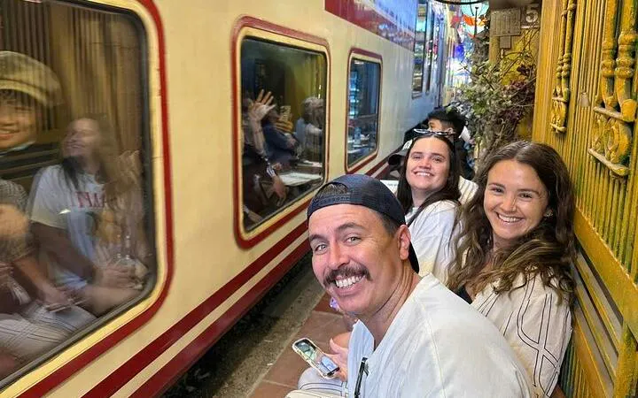 Tourists smiling as a train passes by on Hanoi's Train Street during a cyclo tour.