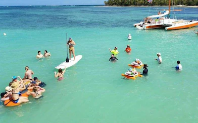 Small group enjoying snorkeling and paddleboarding near a catamaran in Punta Cana.