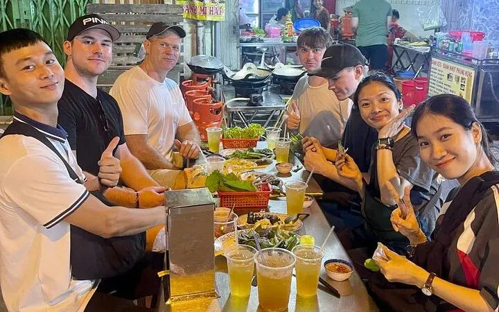 Group enjoying street food at a local eatery during Ho Chi Minh City motorbike tour.