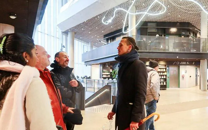 Tour group listening to a guide inside a modern building in Oslo.