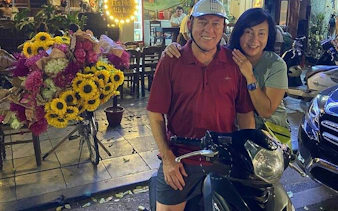 Motorbike parked on Hanoi street at night with flower vendor nearby.