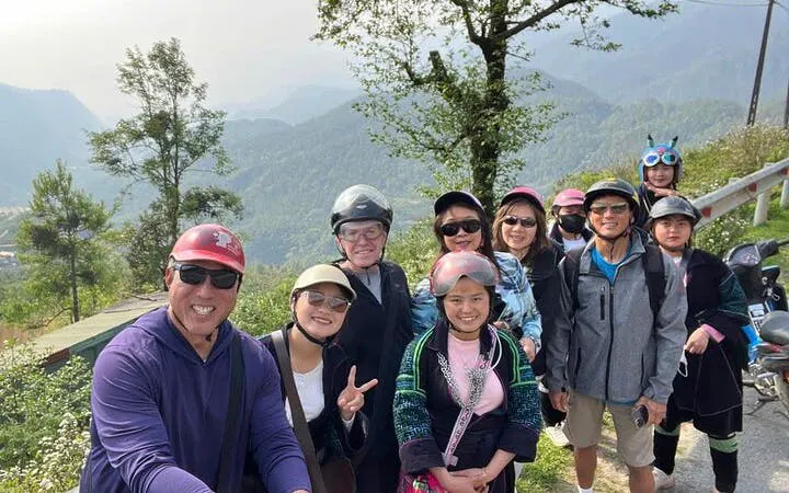 Group of tourists on a motorbike tour in Sapa, Vietnam, with scenic mountain views.