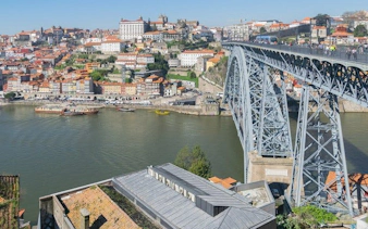 Dom Luís I Bridge spanning Douro River in Porto's historic center, view of cityscape and waterfront.