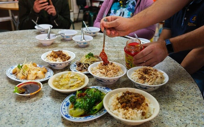 Taipei food tour with locals sampling traditional dishes at a table.