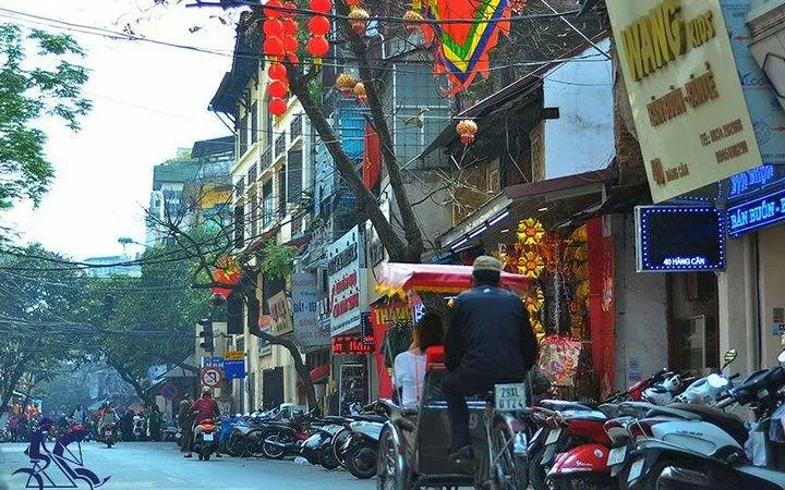 Cyclo ride through Hanoi's Old Quarter with vibrant street decorations and local shops.