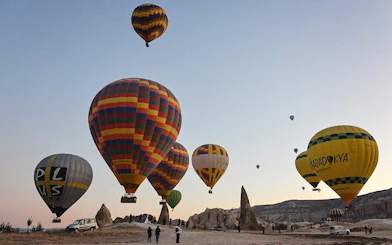 Hot air balloons rising over Cappadocia's unique rock formations at sunrise.