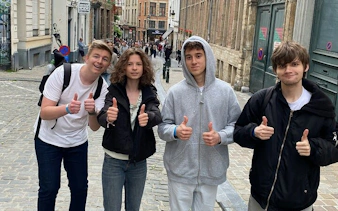 Group of friends giving thumbs up on a cobblestone street in Brussels during a self-guided city exploration game.