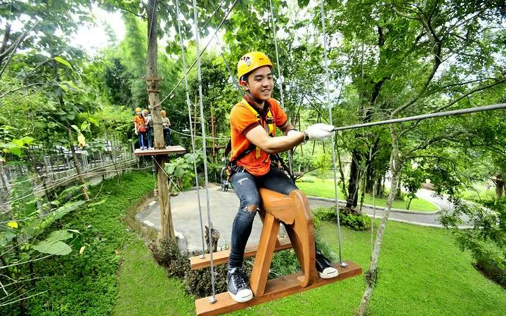 Participant on a zipline course at Phoenix Adventure Park, Chiang Mai, surrounded by lush greenery.