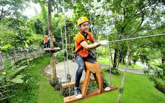 Participant on a zipline course at Phoenix Adventure Park, Chiang Mai, surrounded by lush greenery.