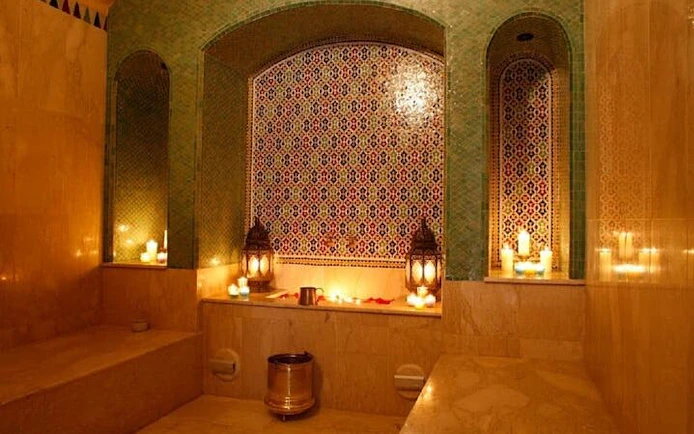 Luxurious Moroccan hammam with candles and ornate tiles in Marrakesh.