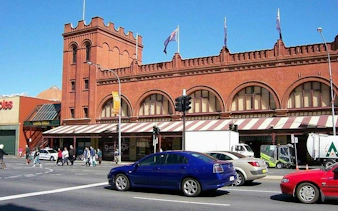 Adelaide Arcade exterior with cars and pedestrians, part of self-guided audio tour.