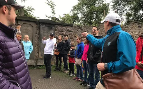 Group on Edinburgh Harry Potter walking tour playing themed games near historic stone wall.