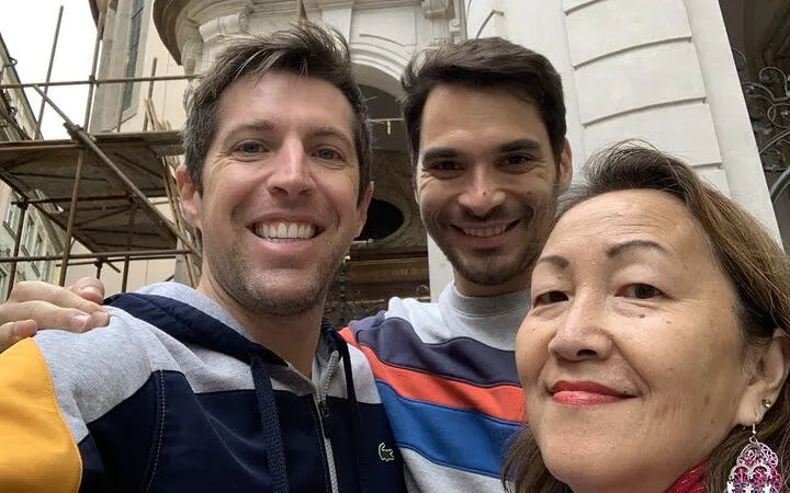 Three people smiling in front of a historic building in Prague.