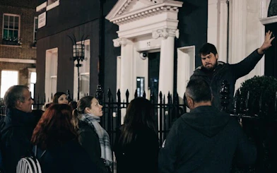 Group on York haunted walking tour listening to guide outside historic building at night.